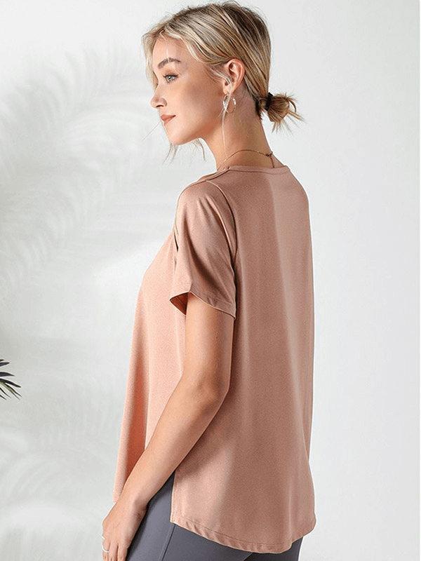 Side view of a woman wearing a loose hollow-out shoulders t-shirt for running in peach color, showcasing breathable and flexible fabric.